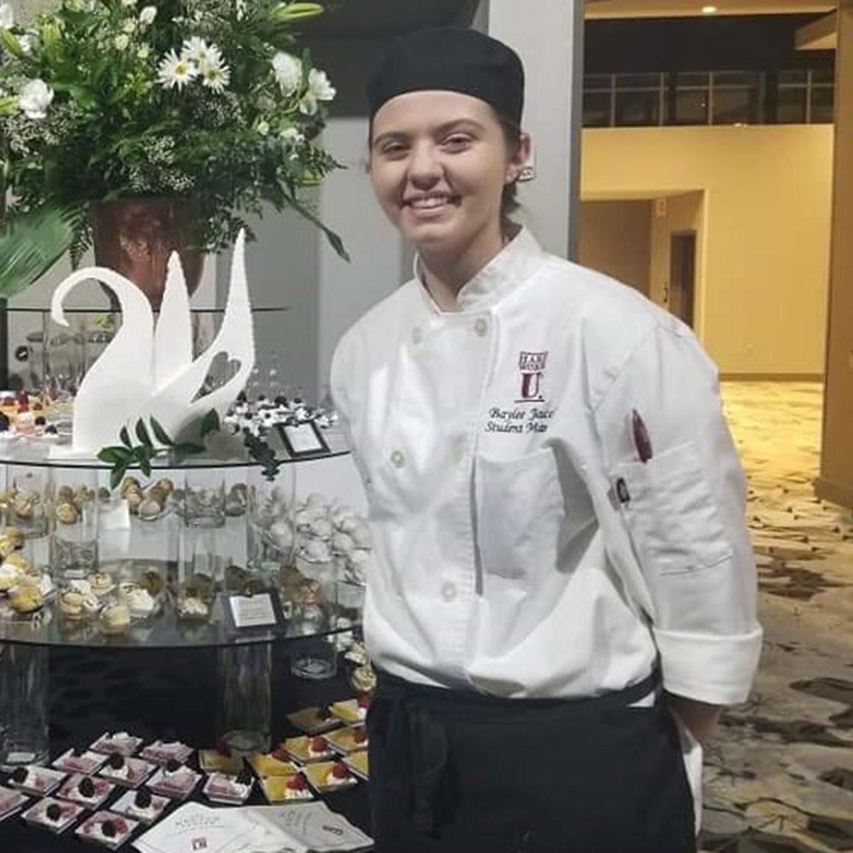 Baylee McKinney stands behind a cart of desserts